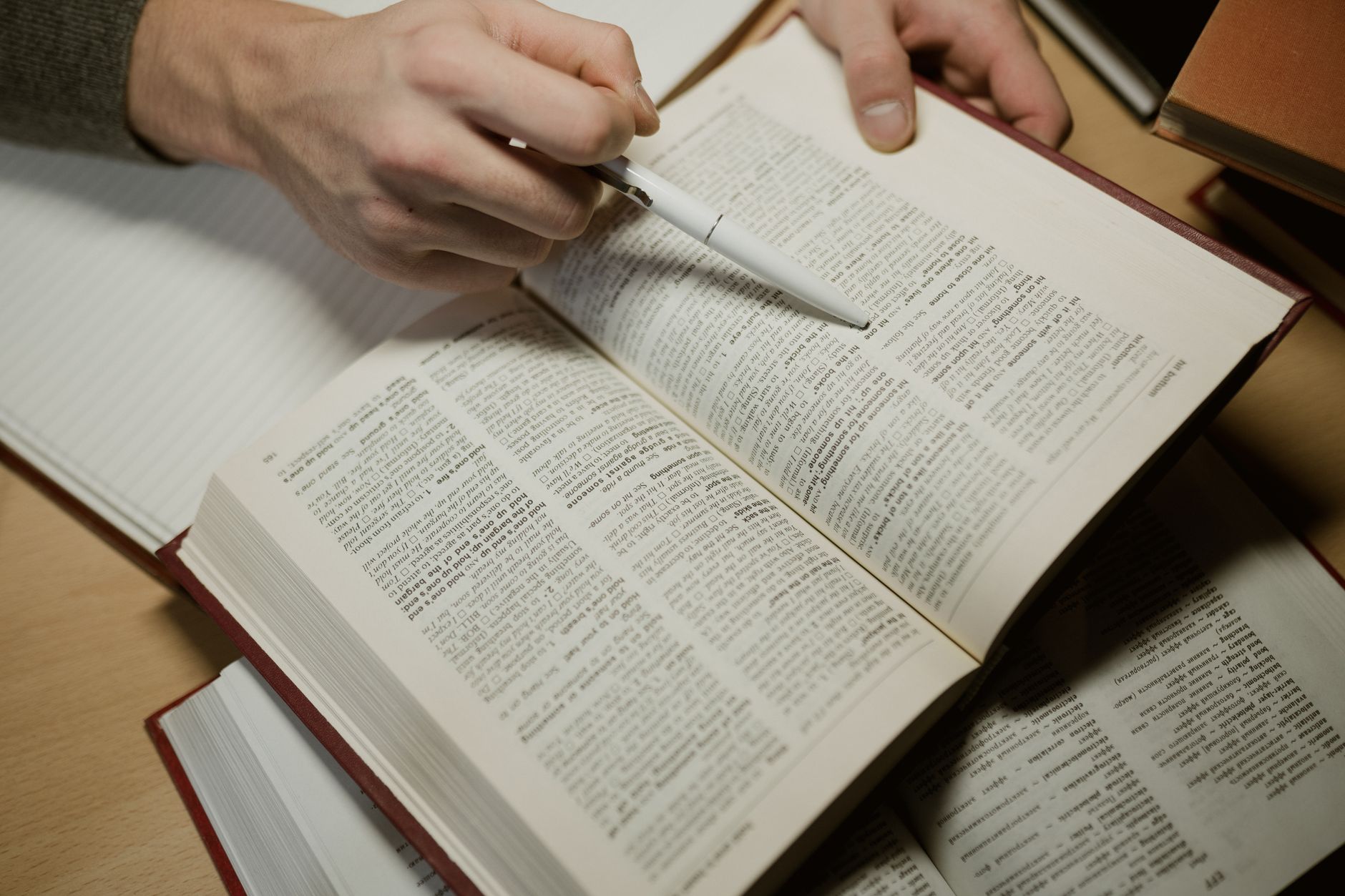 a close up shot of a person holding a pen and an open book