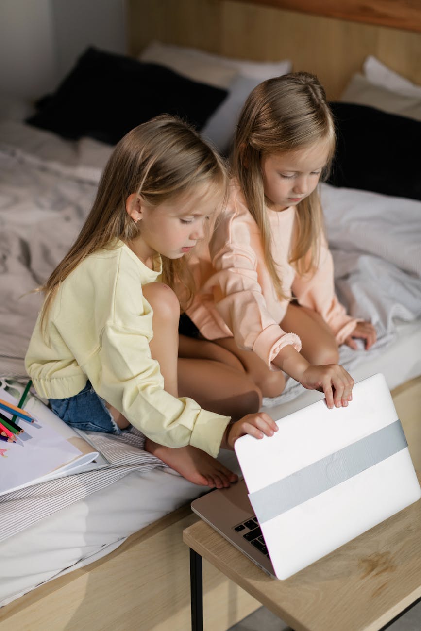 two girls having an online class while sitting on the bed